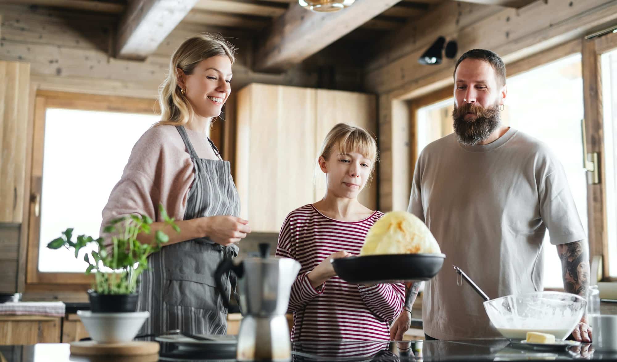Family with small daughter cooking indoors, winter holiday in private apartment.