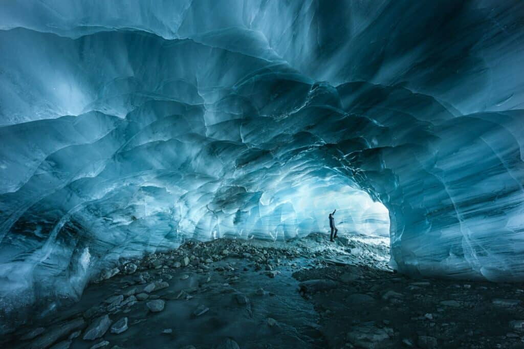 Hiker silhouette exploring an ice cave in the Furgg glacier in Zermatt, Wallis, Switzerland