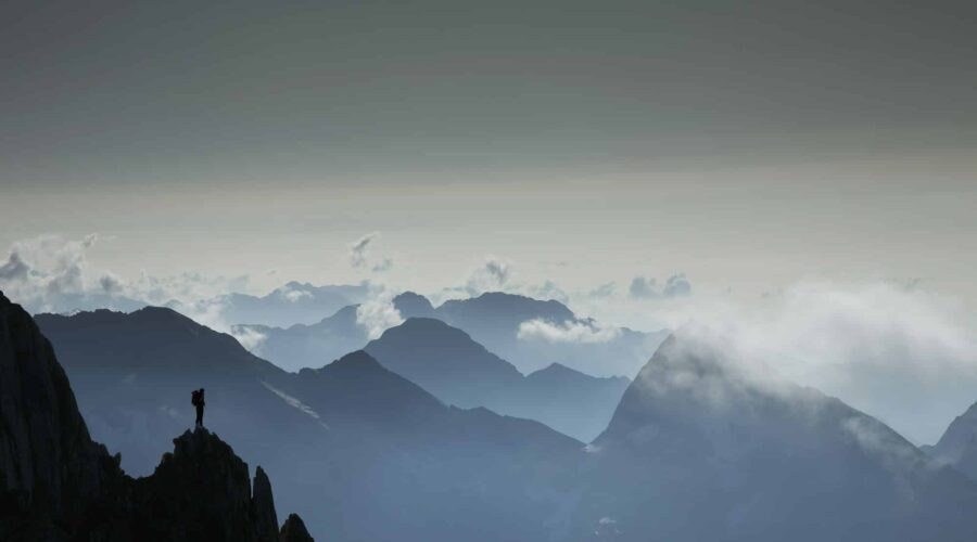 Silhouetted lone climber looking out at mountain view, Zermatt, Canton Wallis, Switzerland